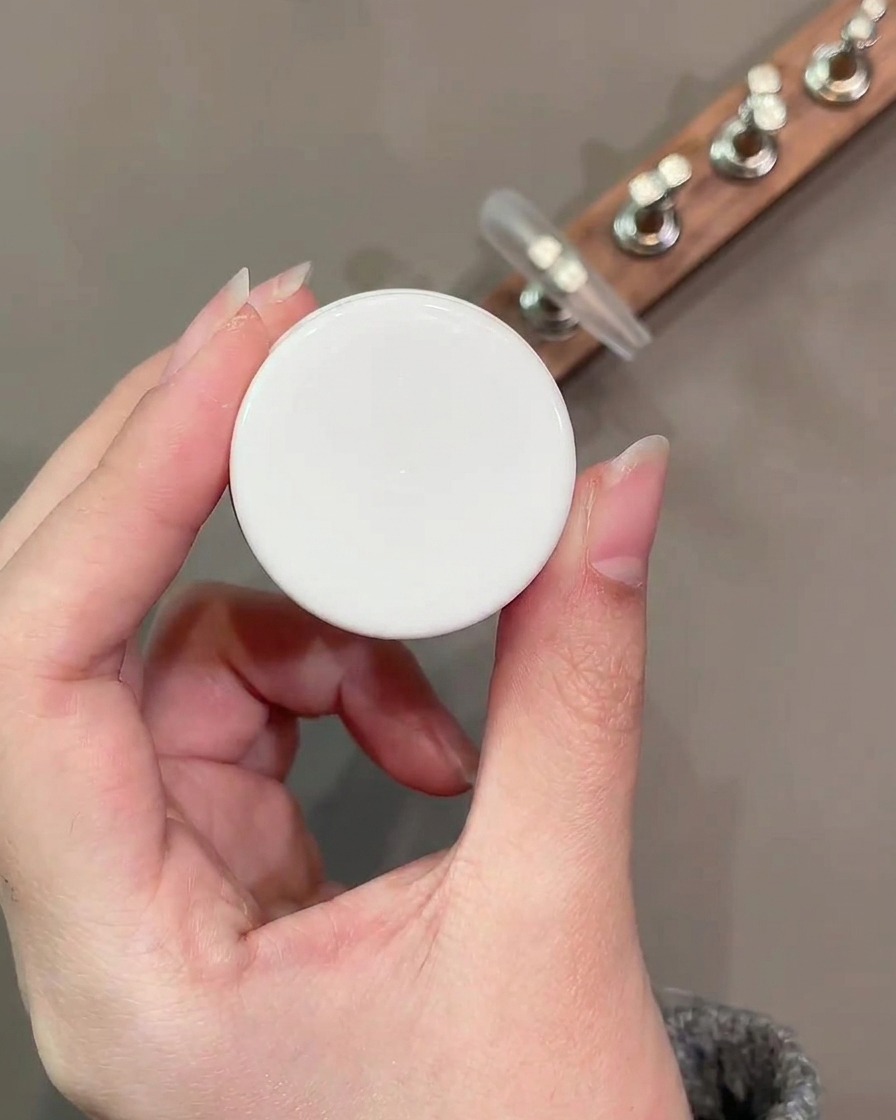 Ein flacher Gelpinsel trägt eine glatte Schicht Nude-Basisfarbe Nummer 34 auf die Nageloberfläche auf.