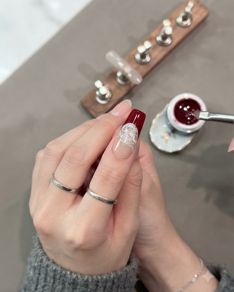 Ein Pinsel füllt den unteren Abschnitt der Nagelspitze vollständig mit dunkelrotem Cat-Eye-Gel aus.