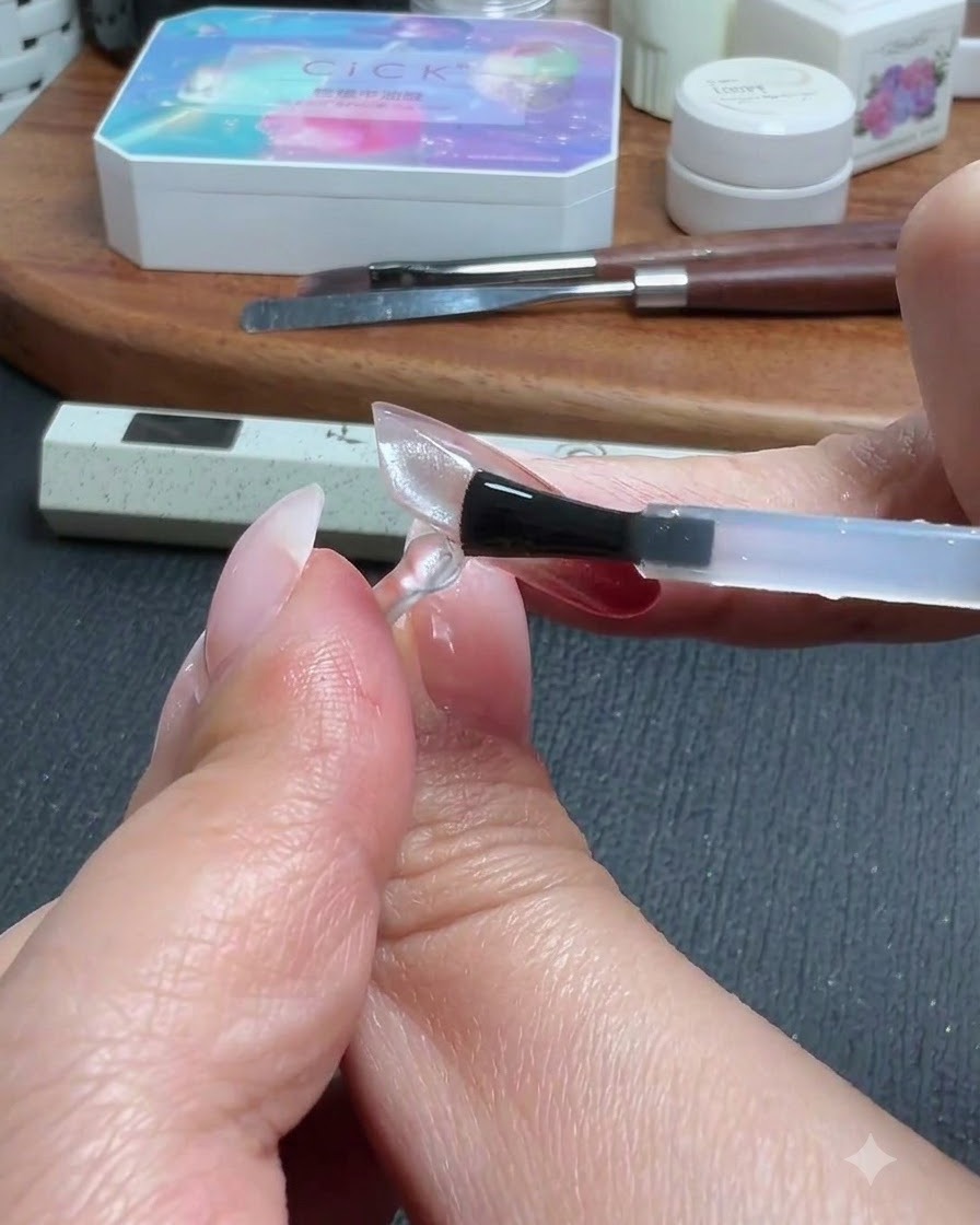 Ein Pinsel trägt eine Top-Coat-Schicht über eine klare, durchsichtige Nagelverlängerung auf.