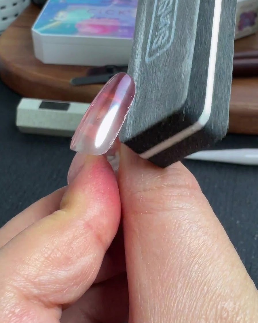 Eine Nagelfeile formt die Seitenkante eines fertigen Chromnagels.