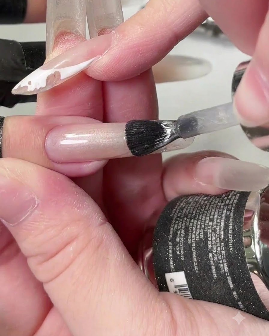 Ein Pinsel trägt klares Kristall Cat-Eye-Gel über die Länge des Nagels auf.