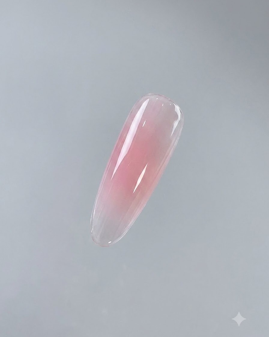 Ein einzelner fertiggestellter Nagel zeigt eine glänzende, ausgehärtete rosa Basisschicht vor neutralem Hintergrund.