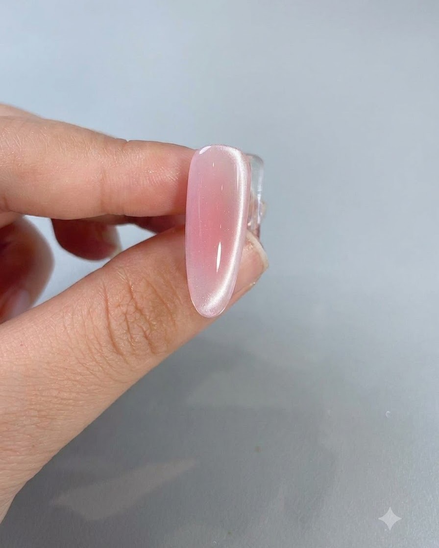 Eine Nahaufnahme eines fertigen rosa Cat-Eye-Nagels zeigt eine helle Lichtreflexionslinie an der Seite.