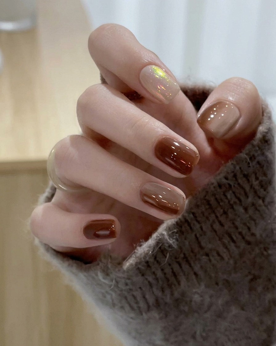 Ein Pinsel gleitet über den Mittelfingernagel und trägt transluzentes Nude-Gel-Polish auf.