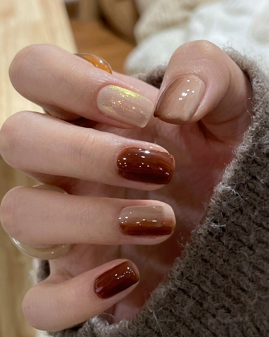 Eine Nahaufnahme eines Nagels zeigt den verschwommenen Übergang zwischen braunem und nudefarbenem Nagellack, um einen glatten Farbverlauf zu bilden.
