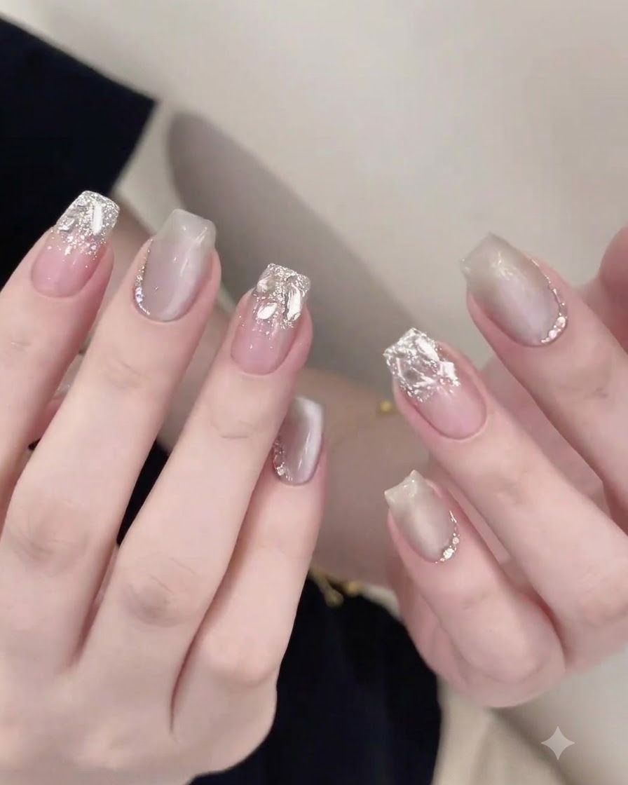 Ein Nagelpinsel trägt sorgfältig einen glänzenden Top Coat um eingebettete Strasssteine auf einem fertigen Nagel auf.