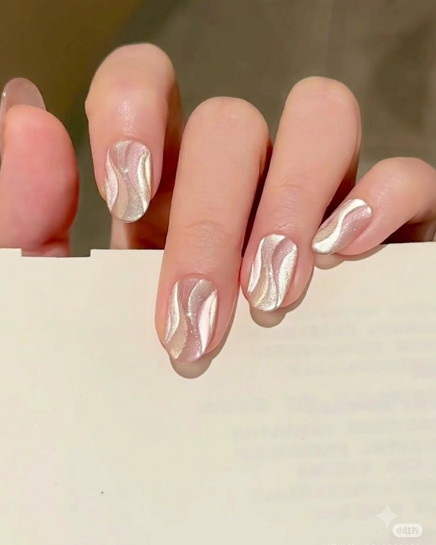 Ein feiner Liner-Pinsel malt eine zweite geschwungene Bandform mit goldenem Cat Eye Gel direkt neben das ausgehärtete silberne Band.