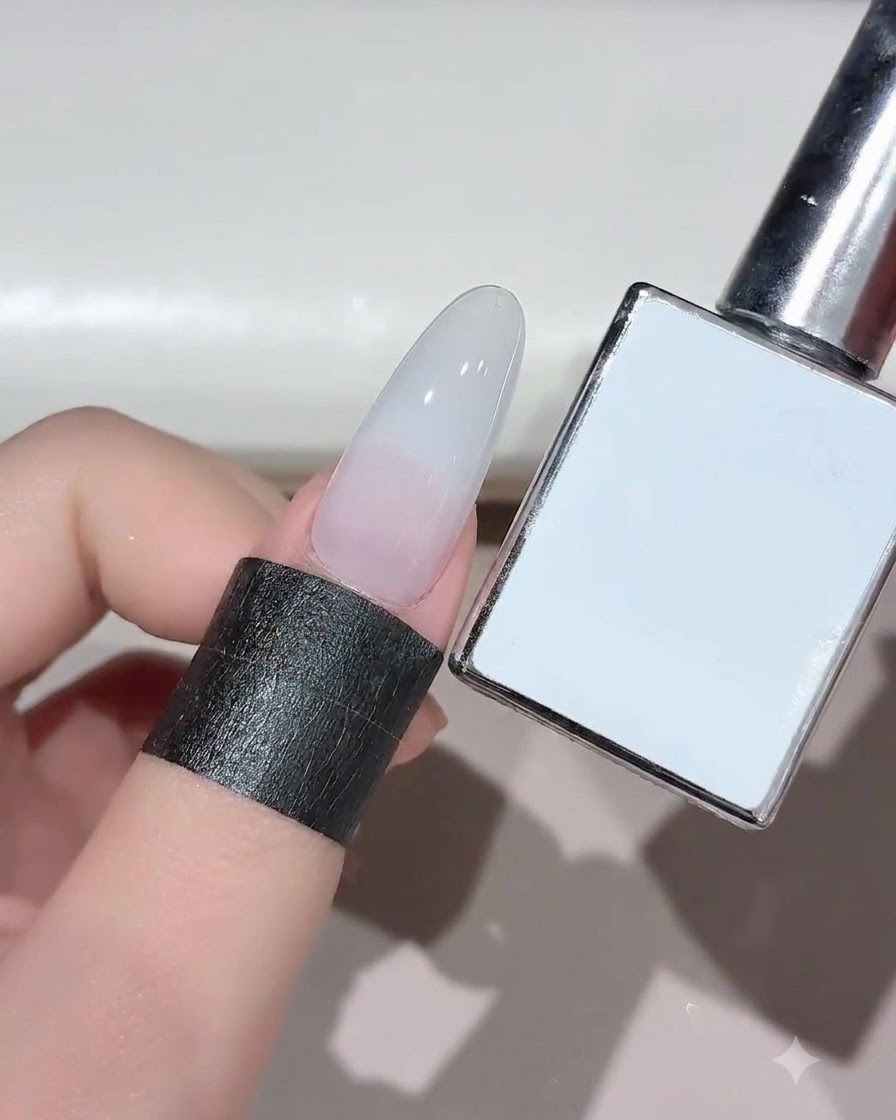Ein Nagel mit ausgehärtetem milchweißem Gel wird neben der dazugehörigen Produktflasche gezeigt.