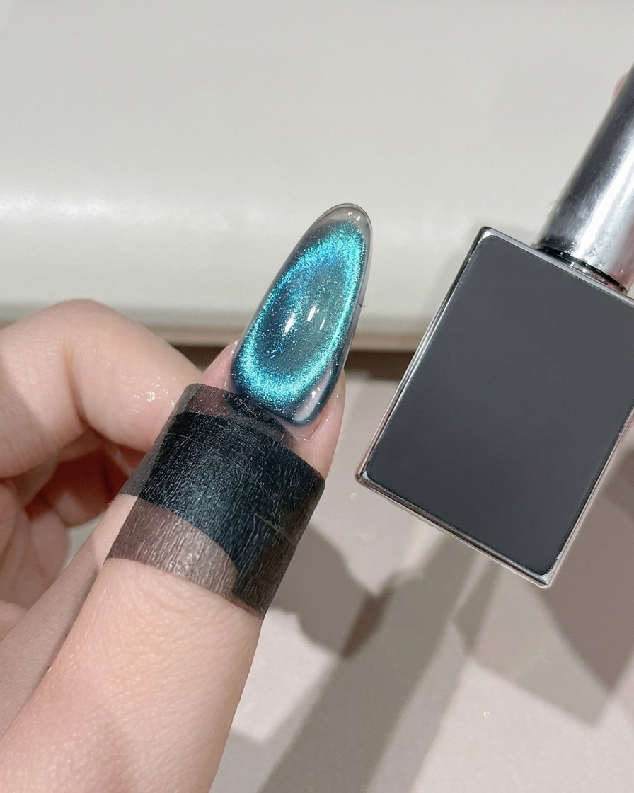 Ein fertiger Cat-Eye-Nagel wird unter einer UV-LED-Lampe neben einer dunklen Gelflasche ausgehärtet.