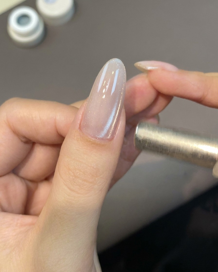Ein kleiner magnetischer Stab schwebt in der Nähe eines Nagels, um die Cat-Eye-Gel-Partikel zu aktivieren.