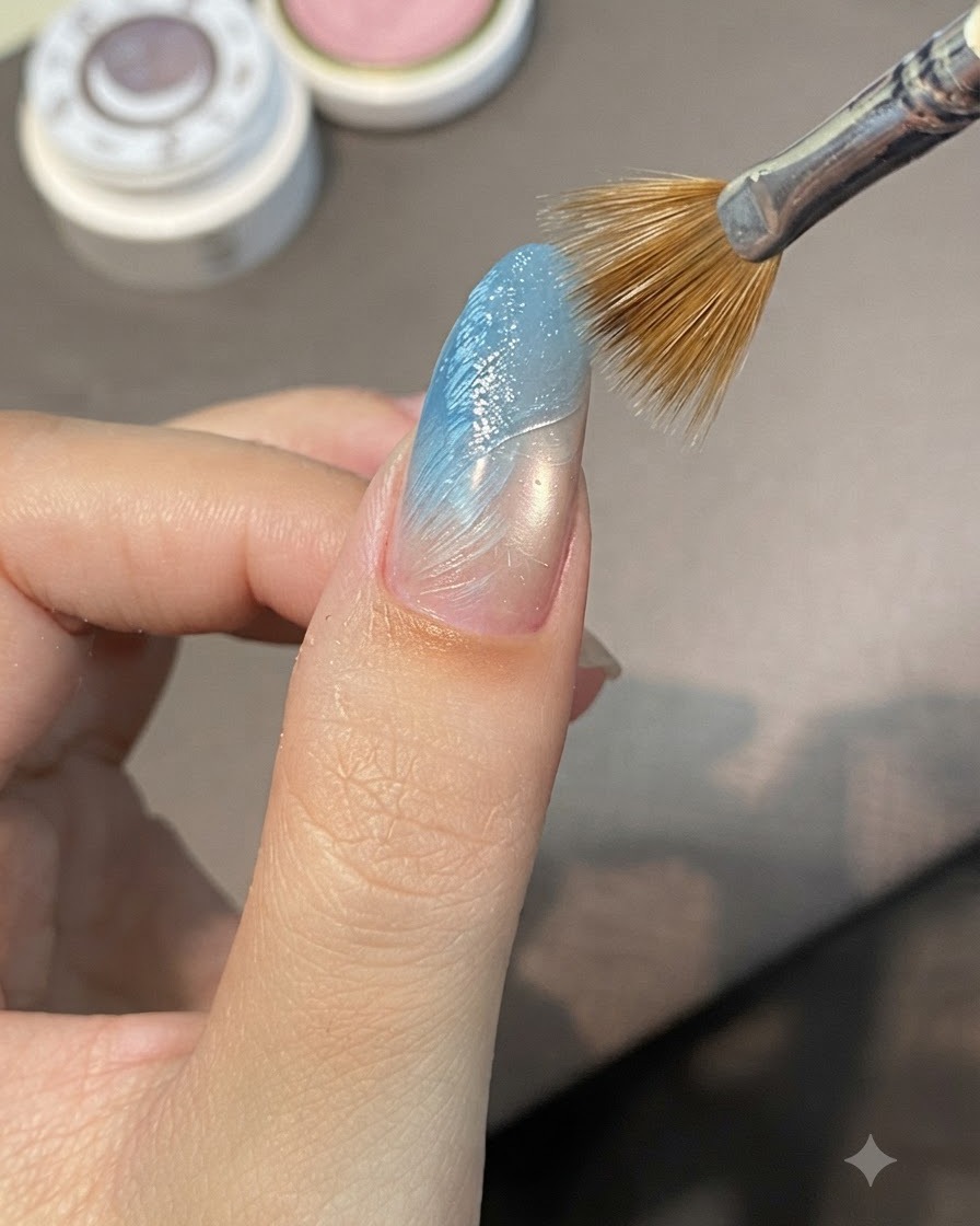 Ein Streifenpinsel zieht sich diagonal über feuchtes Modelliergel auf einem blau graduierten Nagel, um erhabene Rippen zu bilden.