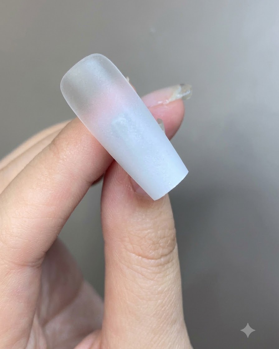 Eine dünne Schicht durchscheinendes, milchig-weißes Gel wird über die Oberfläche des Ombré-Nagels gepinselt.