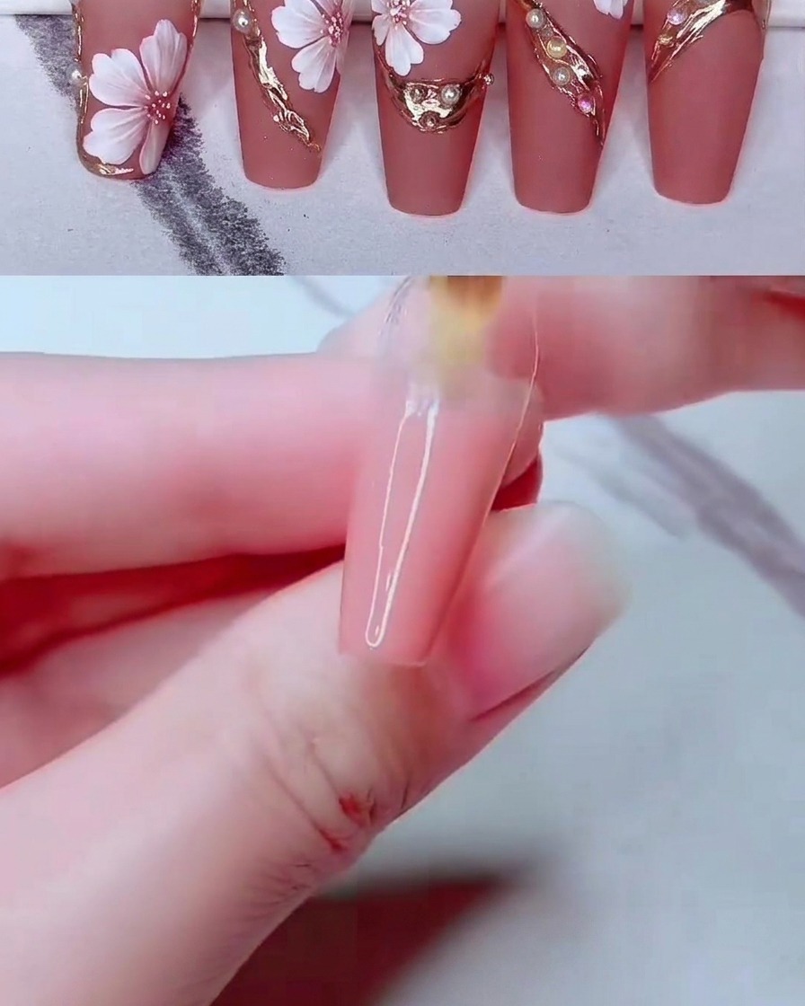 Ein feines Nail-Art-Werkzeug platziert kleine weiße Perlen auf der verzierten Nageloberfläche.