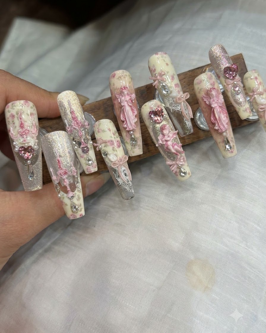 Eine Pinzette platziert einen 3D-Schleifen-Charm und Strasssteine auf einem fertigen Nagel.