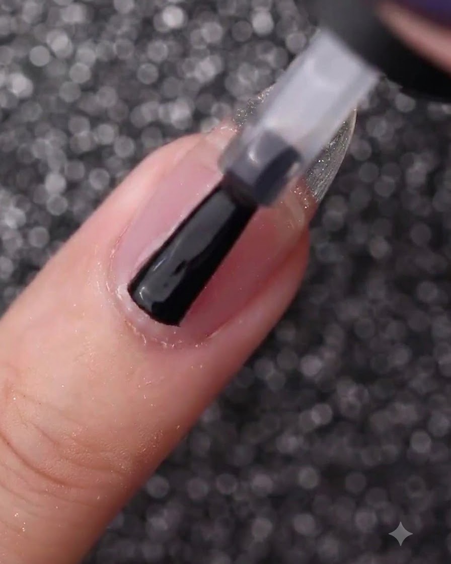 Eine Hand, die mit einem Flaschenpinsel einen unlackierten Naturnagel mit klarem Basis-Gel bestreicht.