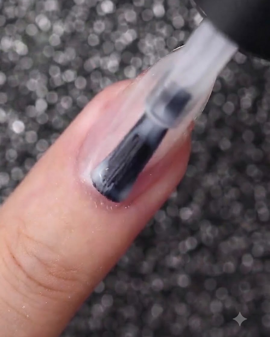 Ein Nagelpinsel, der eine glatte Schicht milchig-weißen Gellack auf einen ovalen Fingernagel aufträgt.