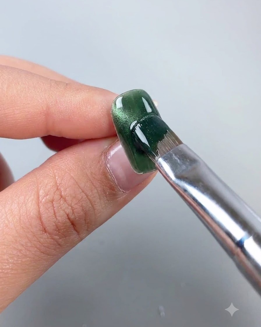 Ein Magnetstab wird in die Nähe eines grünen Cat-Eye-Gel-Nagels gehalten, um die magnetischen Partikel in eine Seitenbogenlinie zu verschieben.