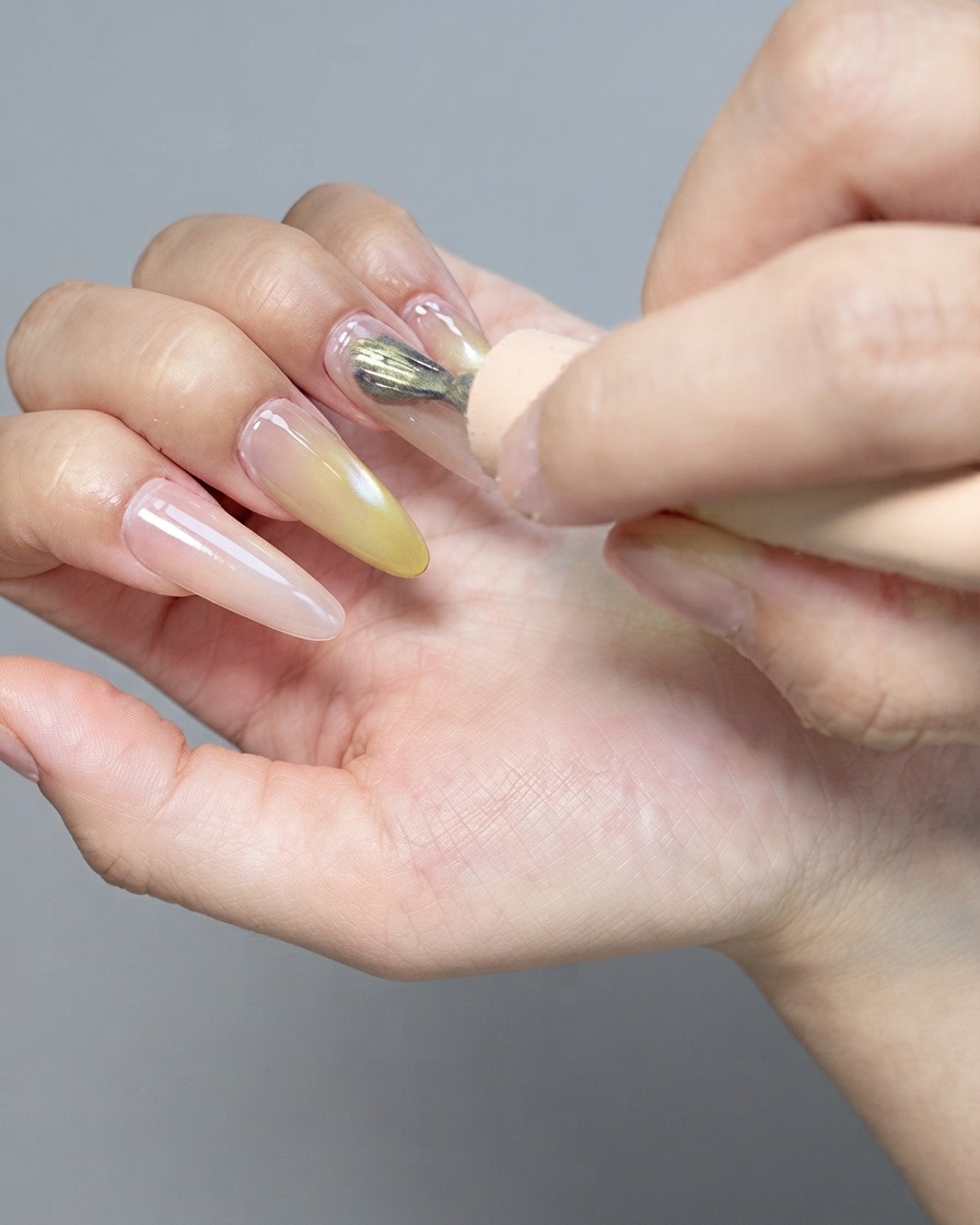 Ein starker Magnet schwebt über einem glänzenden Cat-Eye-Gel-Nagel, um die magnetischen Partikel zu formen.