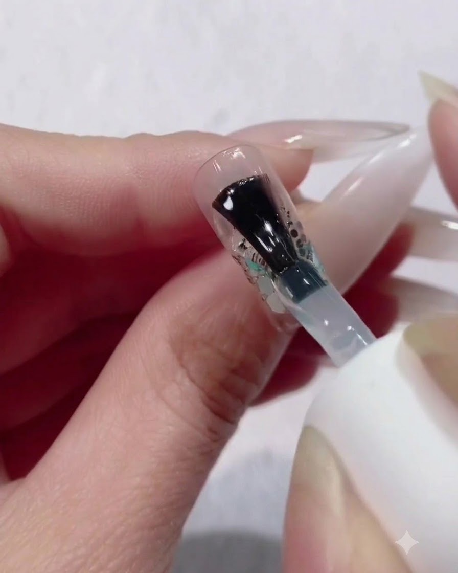 Ein Pinsel trägt eine dicke, großzügige Schicht klarem Builder-Gel über ein Glitzer- und Paillettenverlaufsdesign auf.