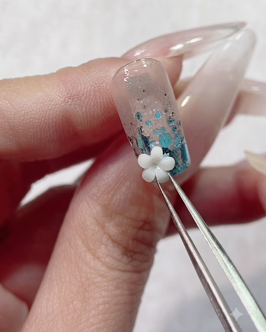 Präzisionspinzetten platzieren einen weißen 3D-Acrylblumen-Charm auf dem feuchten Gel nahe der Nagelhaut.