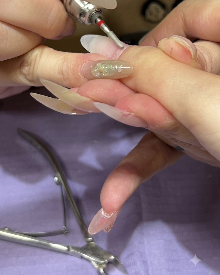 Ein feiner Fräser-Bit bearbeitet den Nagelhautbereich eines Naturnagels.