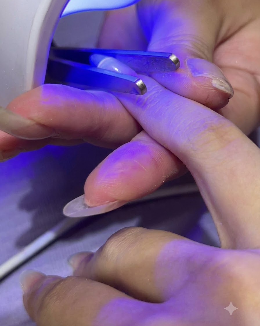Eine tragbare Mini UV/LED Lampe härtet klaren Builder Gel auf einem Fingernagel aus.