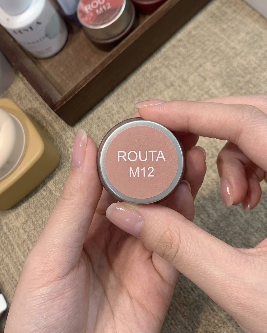 Ein kleines Glas mit der Aufschrift Routa M12, das ein warmes pfirsich-rosafarbenes Blush-Gel enthält.