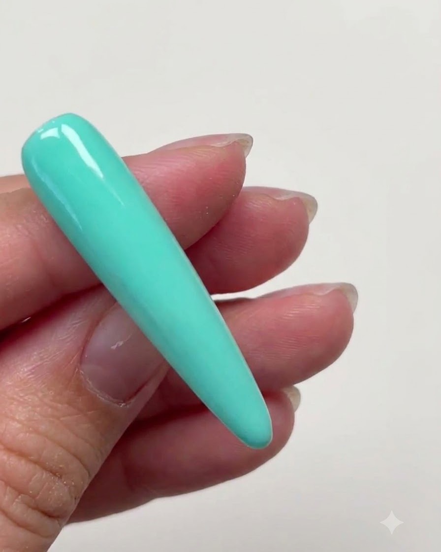 Eine lange Stiletto-Nagelverlängerung, die vollständig mit einer glatten Schicht mintgrünen Farbgets bedeckt ist.