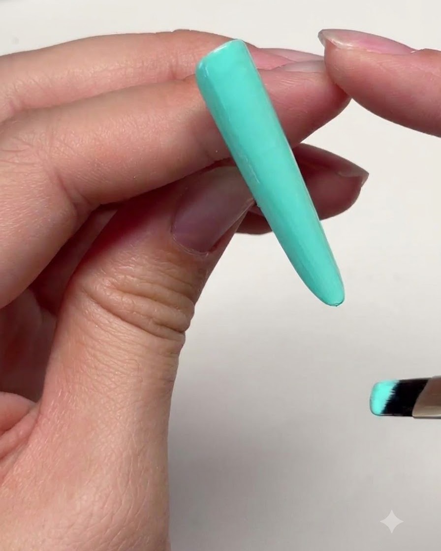Eine lange mintgrüne Nagelverlängerung mit einer dünnen Gelschicht, die in der Nähe der oberen Nagelhautgrenze aufgetragen wurde.