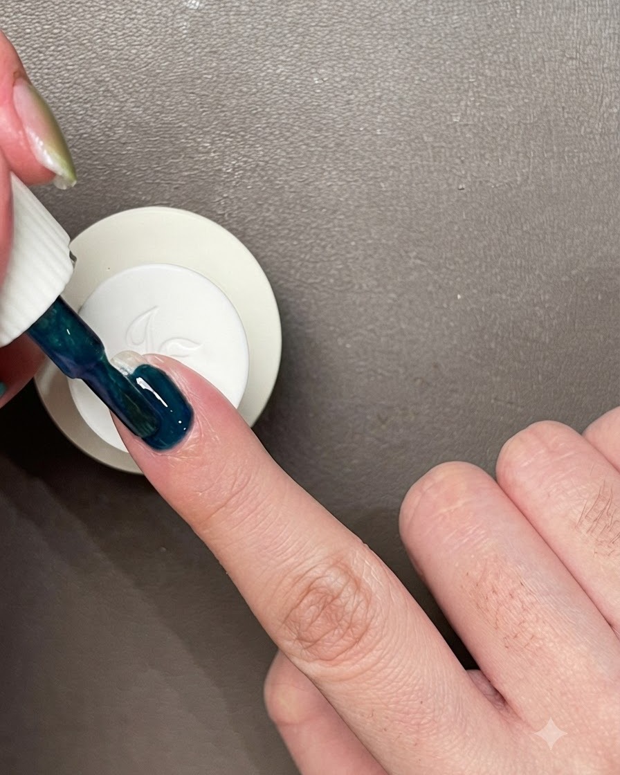 Auftragen einer Schicht dunkelblau-grünen Gel-Lacks direkt auf einen unlackierten Naturnagel.