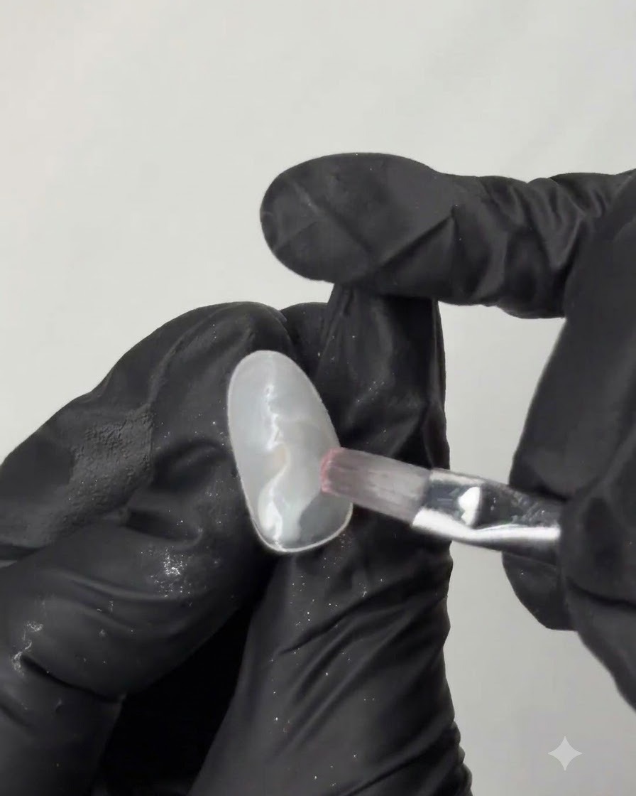 Ein flacher Pinsel glättet mintgrünen Gel-Nagellack über die Oberfläche einer ovalen Nagel-Übungsspitze.