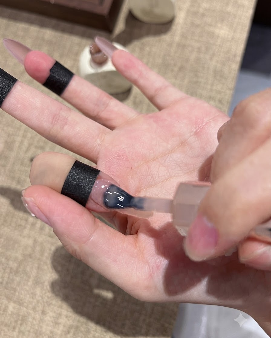 Ein Nagelpinsel trägt violettes Cat-Eye-Gel auf die Nagelspitze auf, um einen Ombré-Effekt zu erzielen.