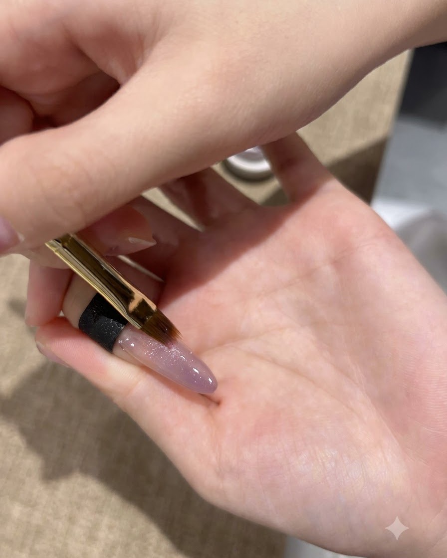 Ein feiner Pinsel trägt eine zweite Schicht violettes Cat-Eye-Gel auf die Nagelspitze auf.