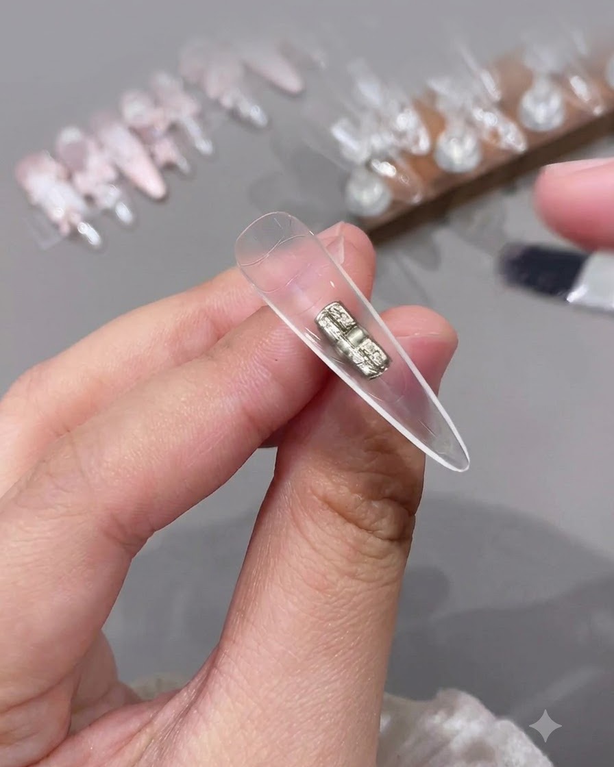 Ein kleiner Pinsel trägt einen klaren Top Coat auf die innere Hohlseite einer künstlichen Klarsicht-Nagelspitze auf.
