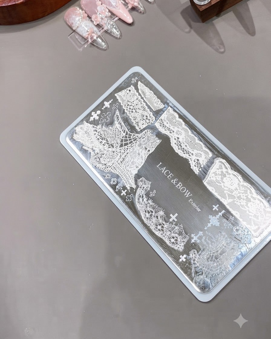 Ein transparenter Silikon-Nagelstamper liegt neben einer gravierten Metallplatte mit komplizierten weißen Spitzenmustern bereit.