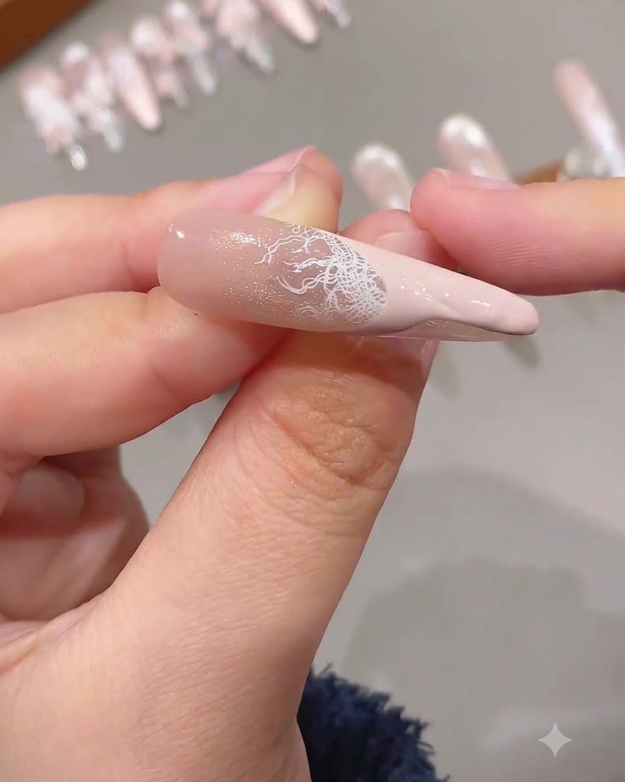 Eine fertige French-Spitze mit einem filigranen weißen Spitzenmuster kombiniert mit einer einfarbigen rosa Nagelspitze auf einem verlängerten Nagel.