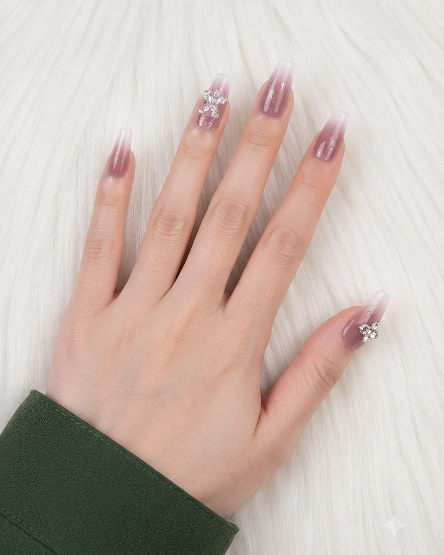 Eine Hand mit fertiggestellten Farbverlaufsnägeln und auf dem Ringfinger und Daumen platzierten Charms.