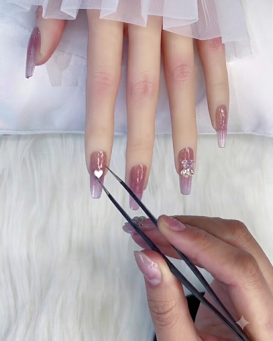 Eine Metallpinzette hält eine kleine weiße herzförmige Verzeihung direkt über dem Nagel eines Zeigefingers.
