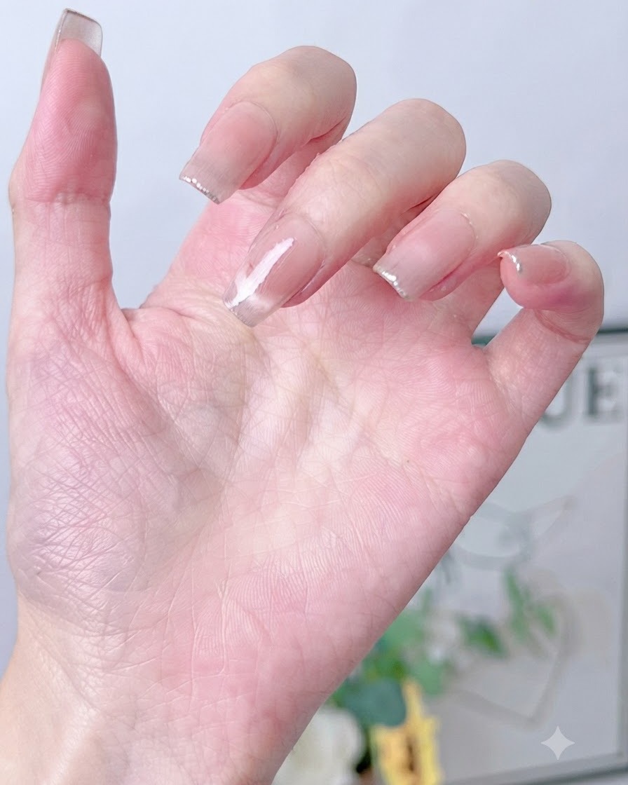 Ein Schwämmchen tupft vorsichtig champagnergoldenen Schimmerlack auf die Spitze eines rosa lackierten Nagels.