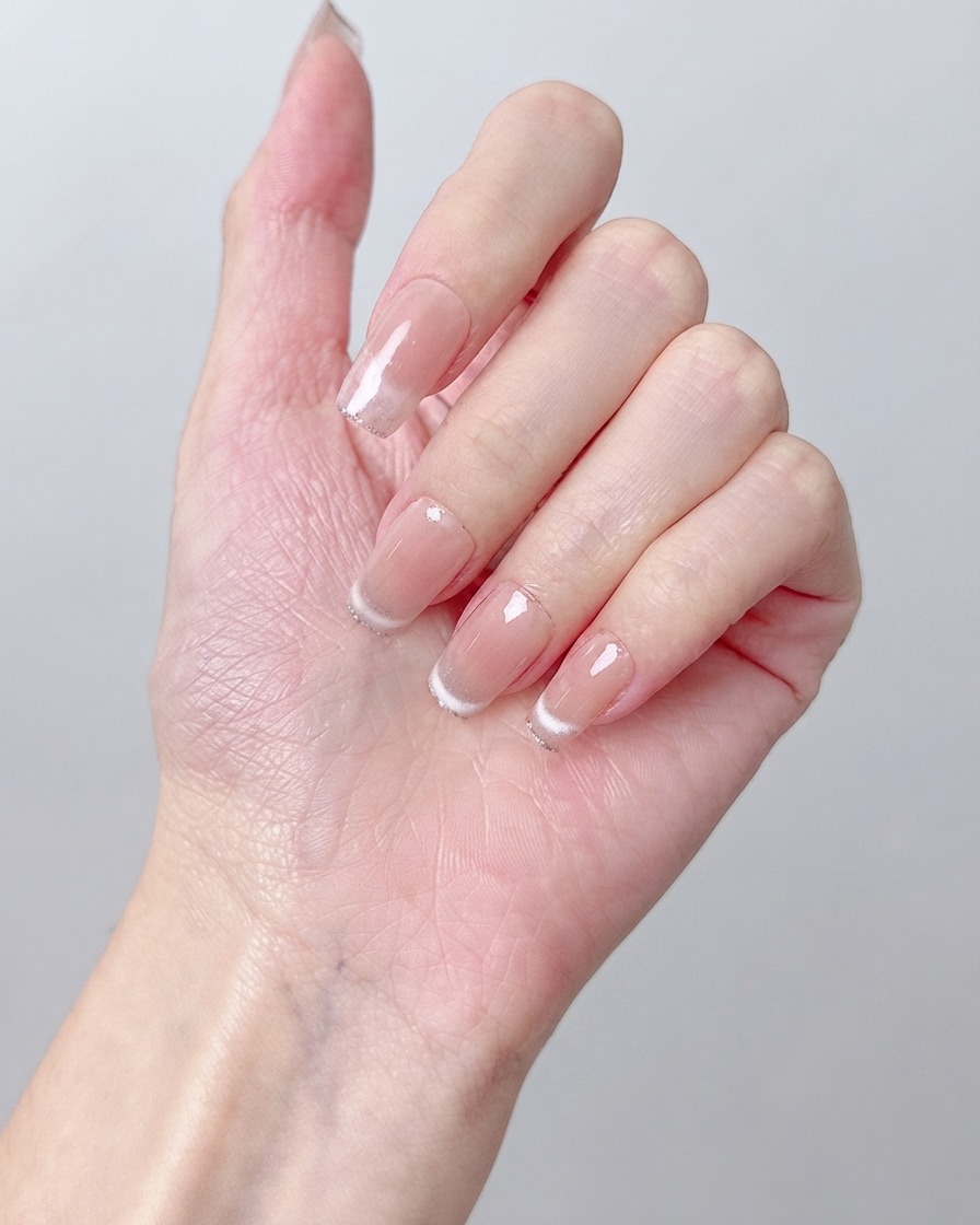 Nahaufnahme eines Nagelpinsels, der champagnergoldene Pigmente zur Mitte eines gepflegten Nagels hin verblendet.