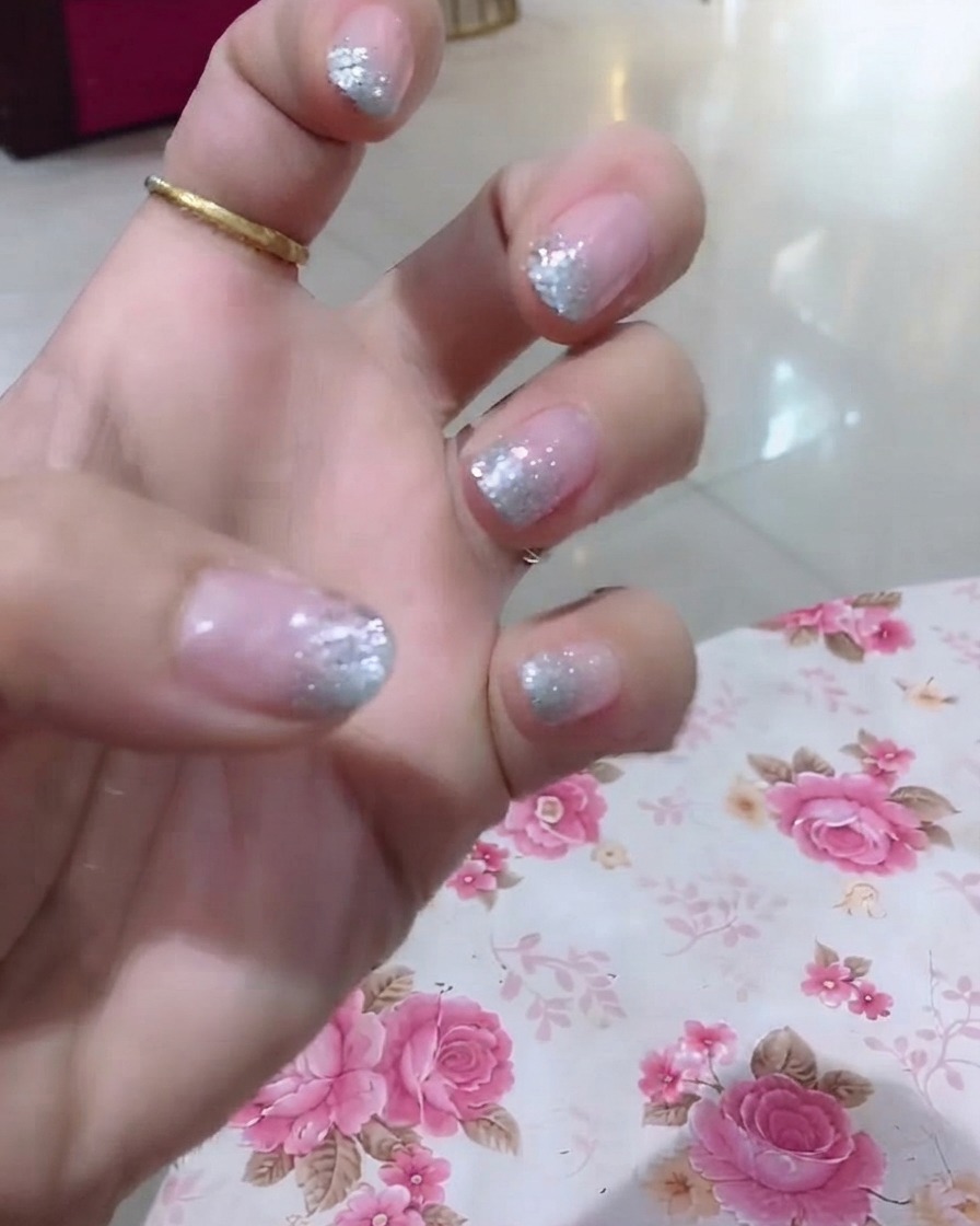 Eine Nahaufnahme einer Hand, die den Ringfinger mit Glitzer und feinen Wortdetails hervorhebt.