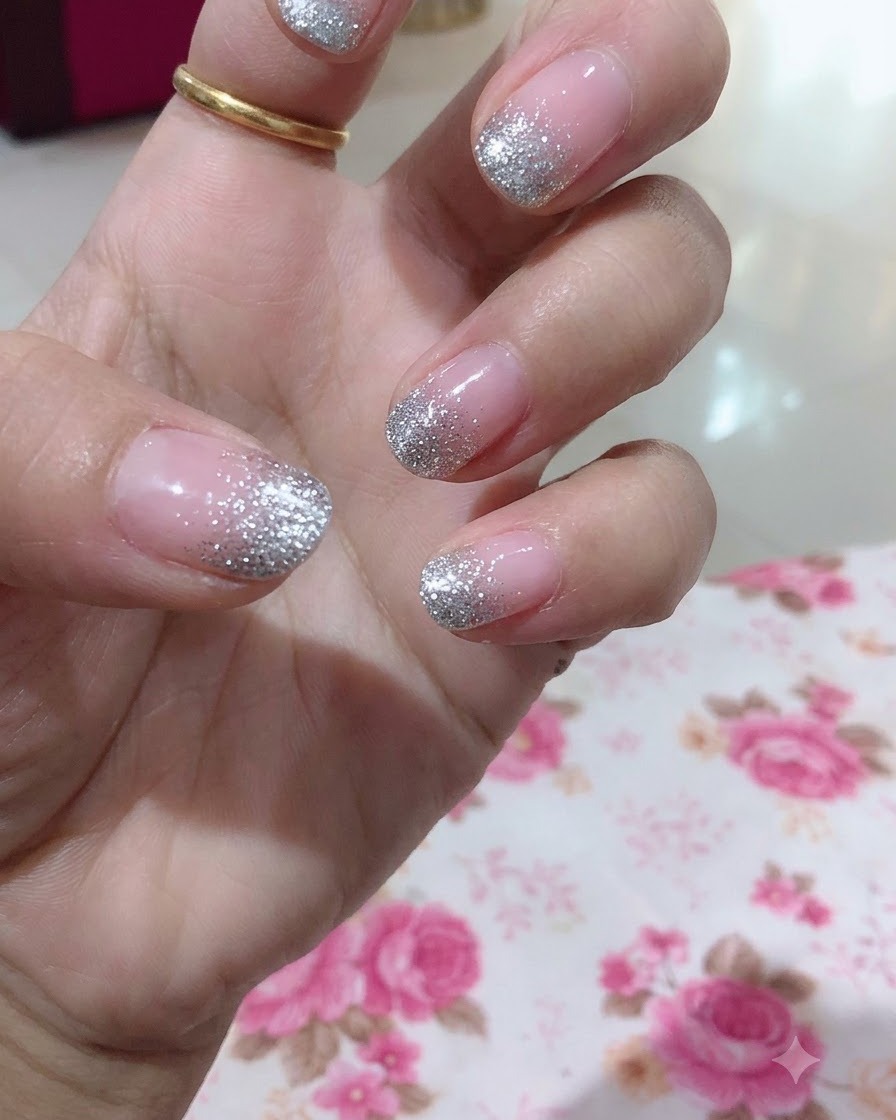 Eine Nahaufnahme einer Hand, die den Mittelfinger mit einem detaillierten silbernen Glitzer-Gradient-Design hervorhebt.