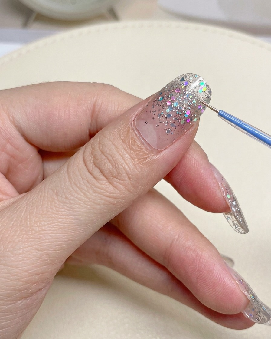 Eine Nahaufnahme von Nagelknipsern aus Metall, die den überschüssigen Rand eines Nagelstickers abschneiden.