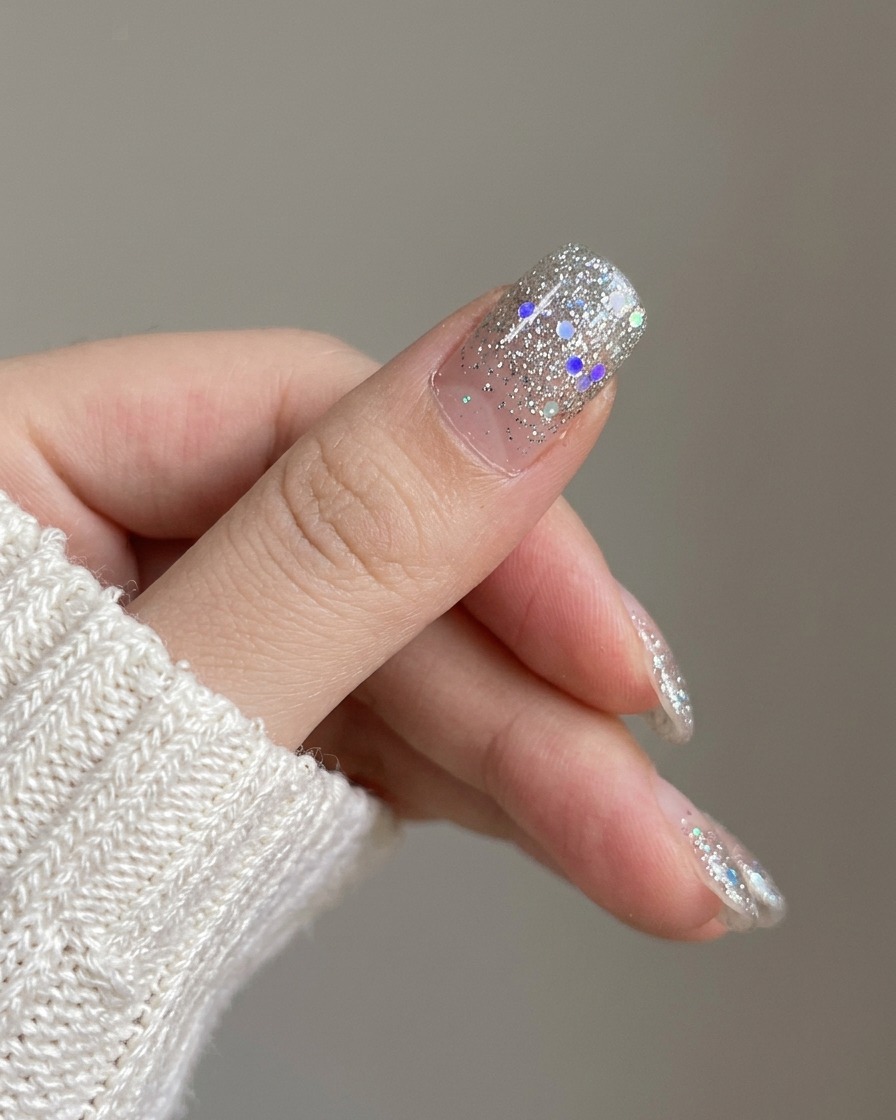Nahaufnahme des frisch aufgebrachten Silber-Glitter-Nagels neben unlackierten Nägeln.