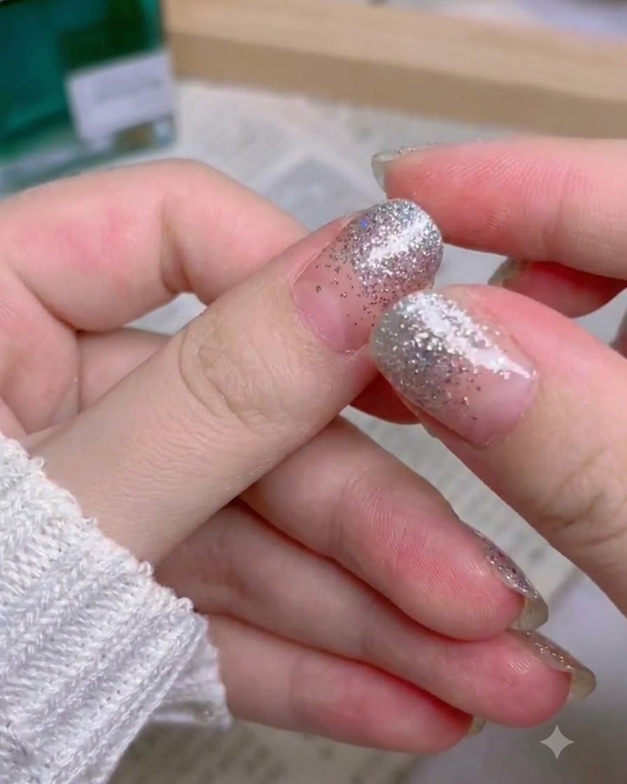 Eine Hand zeigt das vollständige Set an Silber-Glitter-Gradient Press-On-Nägeln.