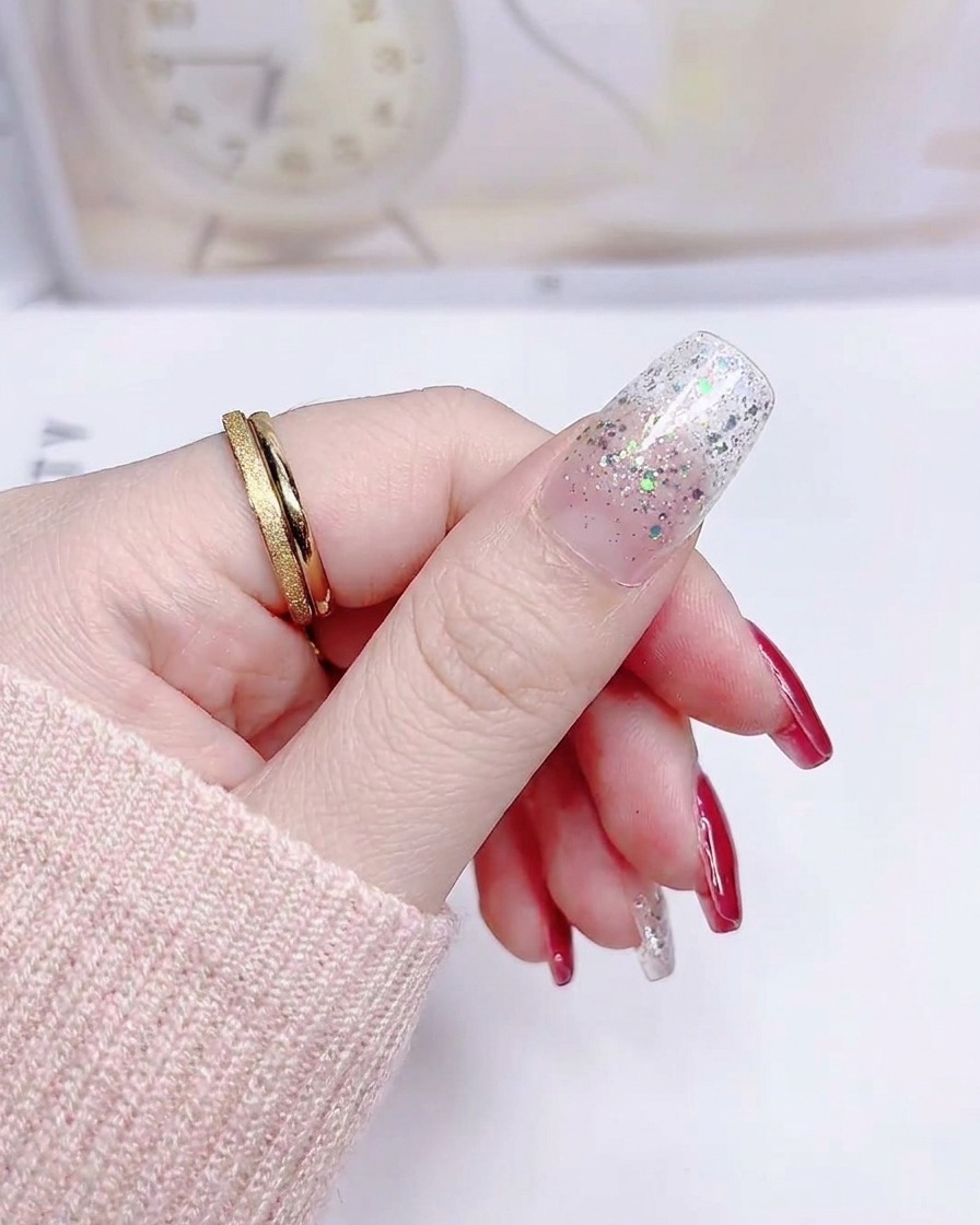 Ein Daumennagel mit einem glatten Silberglitter-Gradient-Sticker, der von der Nagelhaut bis zur Spitze aufgeklebt ist.