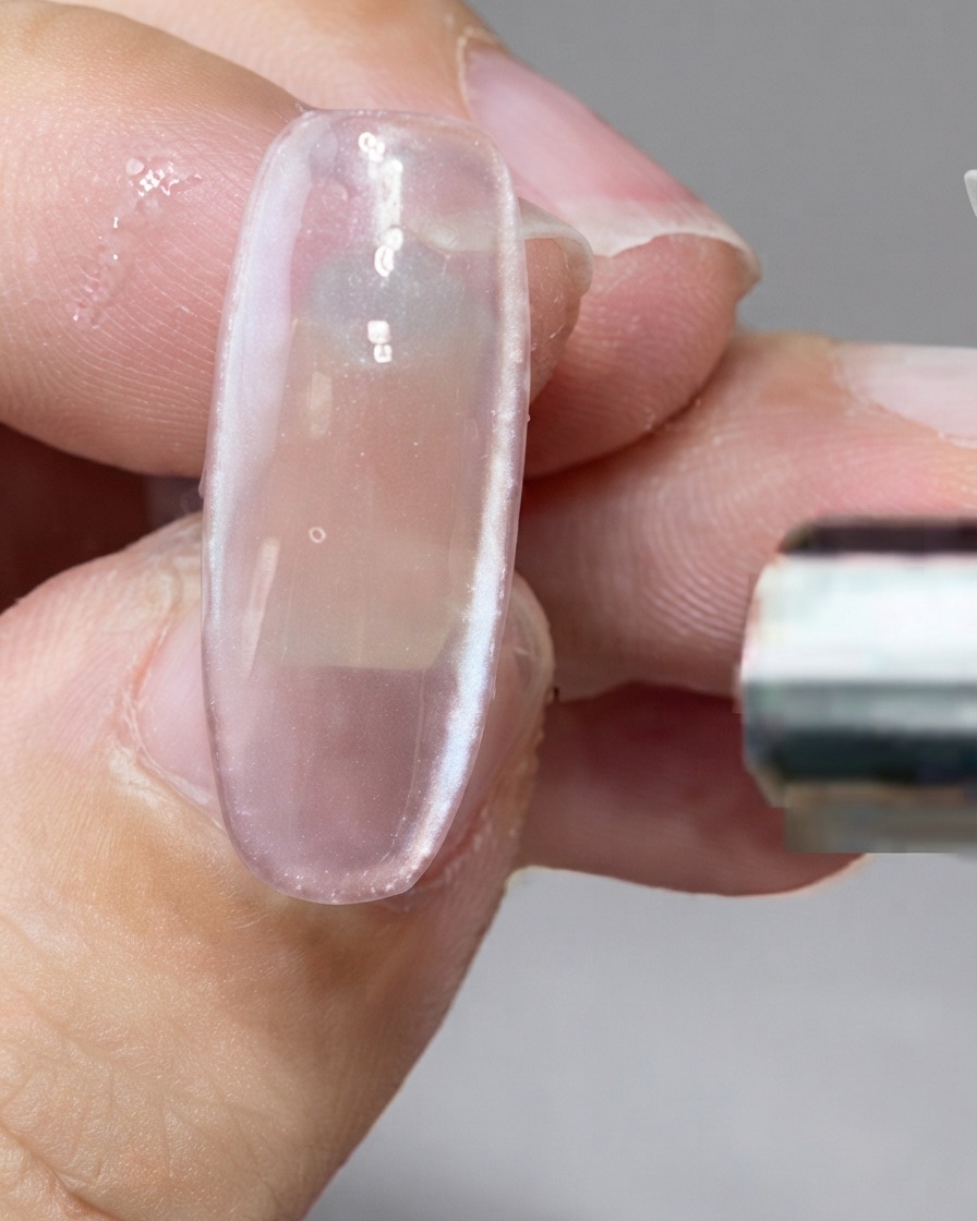 Ein Stabmagnet hält Magnetpartikel entlang der rechten Seite eines Nagels fest.