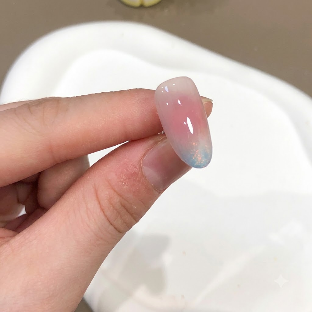 Eine Nahaufnahme eines Nagels mit einem rosa- und blauen Aurora-Pulver-Effekt und Hochglanz-Finish.