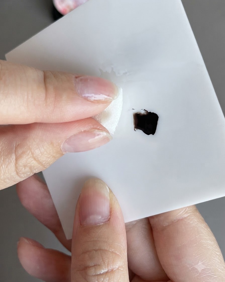 Ein Schwamm nimmt schwarzen Gel-Lack auf und tupft ihn auf ein weißes Memo-Pad.