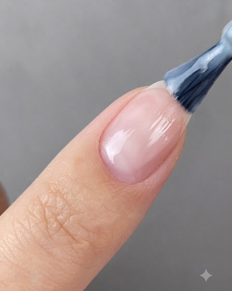 Ein Nagelpinsel trägt transluzentes weißes Gel auf einen vorbereiteten Fingernagel auf.